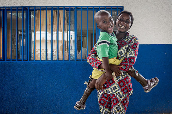 A child is laughing as they are being held by their mother, who is also smiling. Democratic Republic of Congo (DRC). 