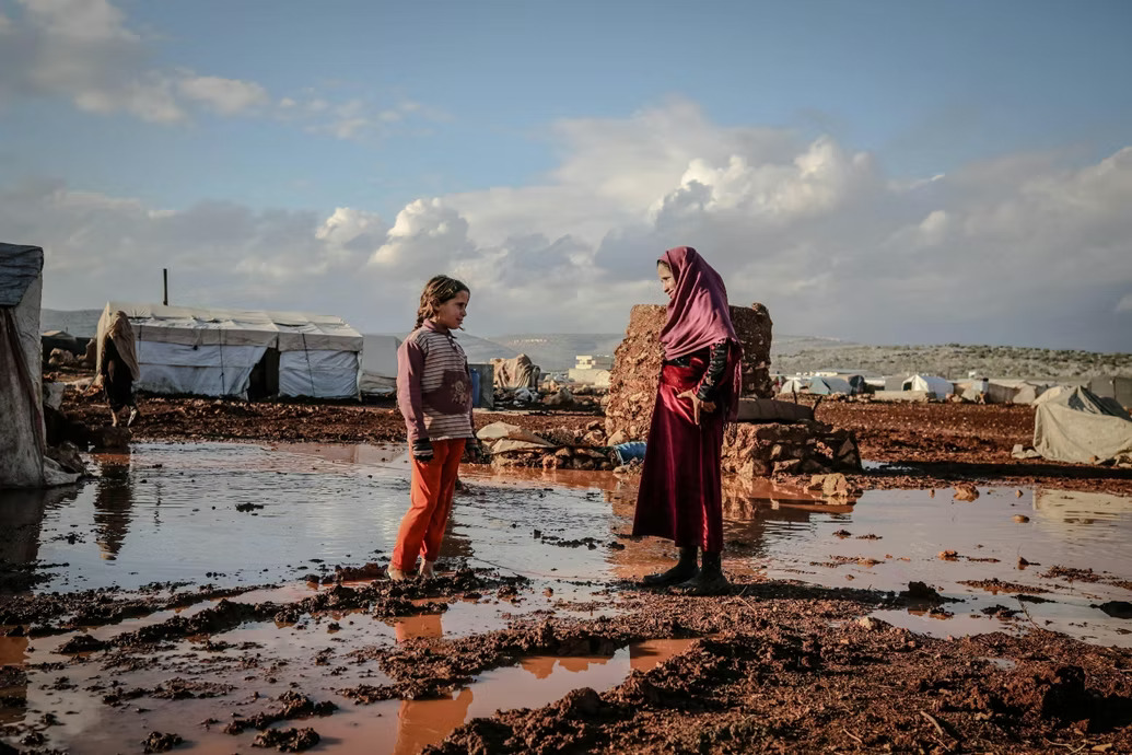 Woman and young girl standing in flooded camp